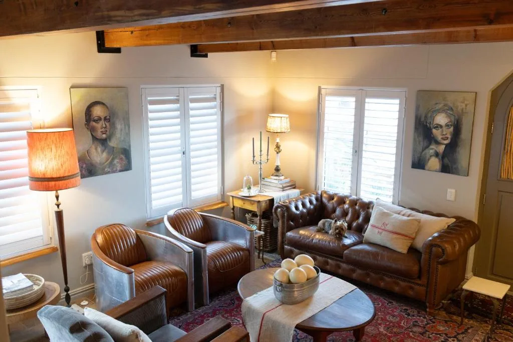 Elegant lounge with leather sofa, armchairs, exposed beams, and portrait artwork