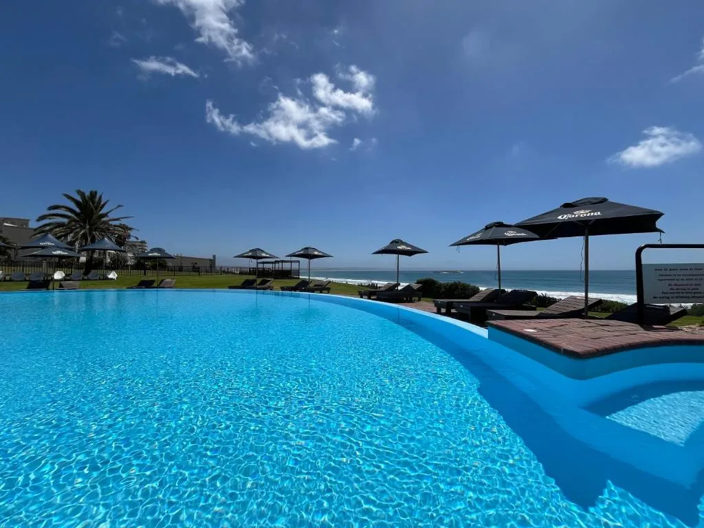 Sparkling oceanfront swimming pool with umbrellas and coastal views