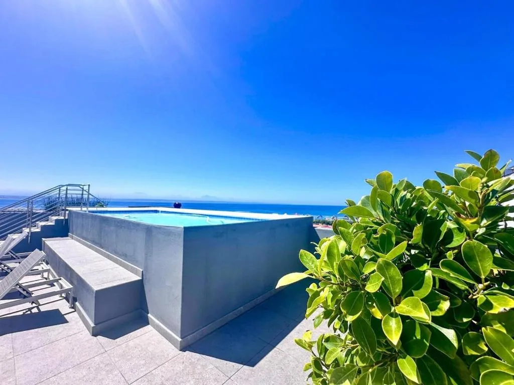 Infinity pool overlooking ocean with coastal views and clear blue sky