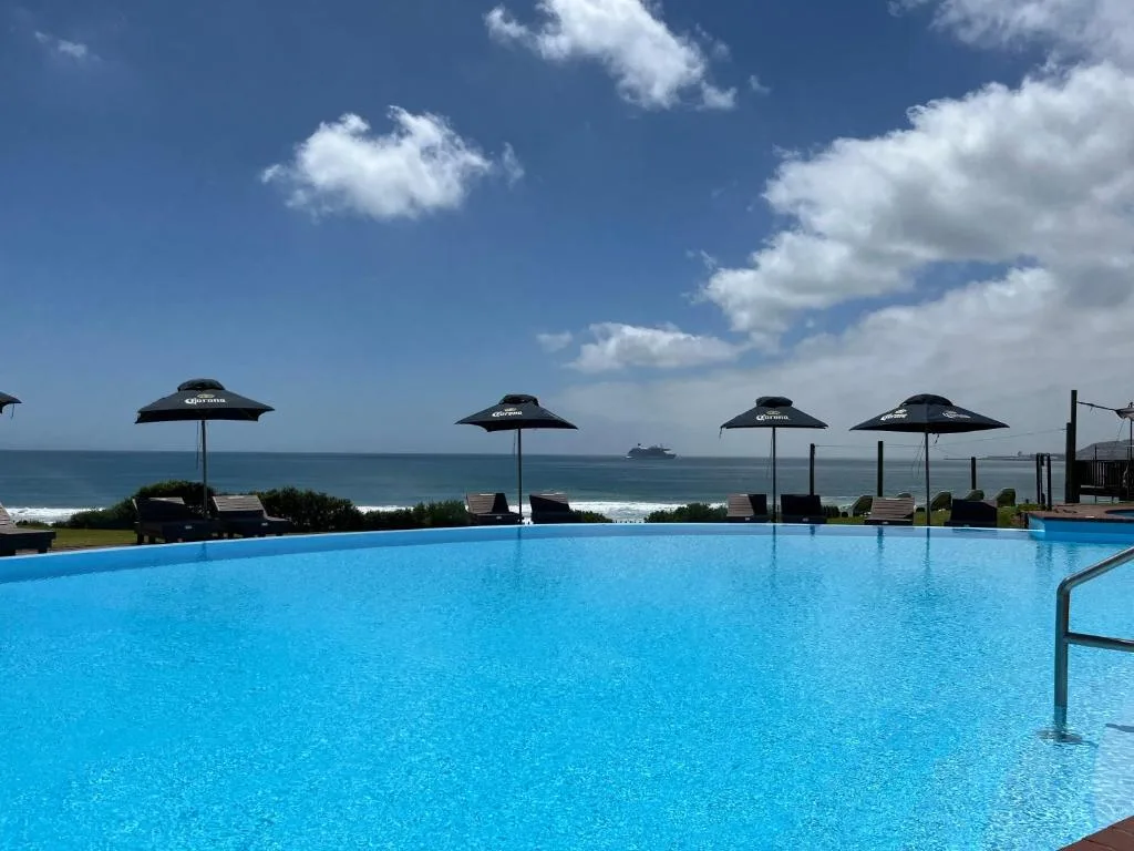 Sparkling blue pool with ocean view and black umbrellas overlooking the sea