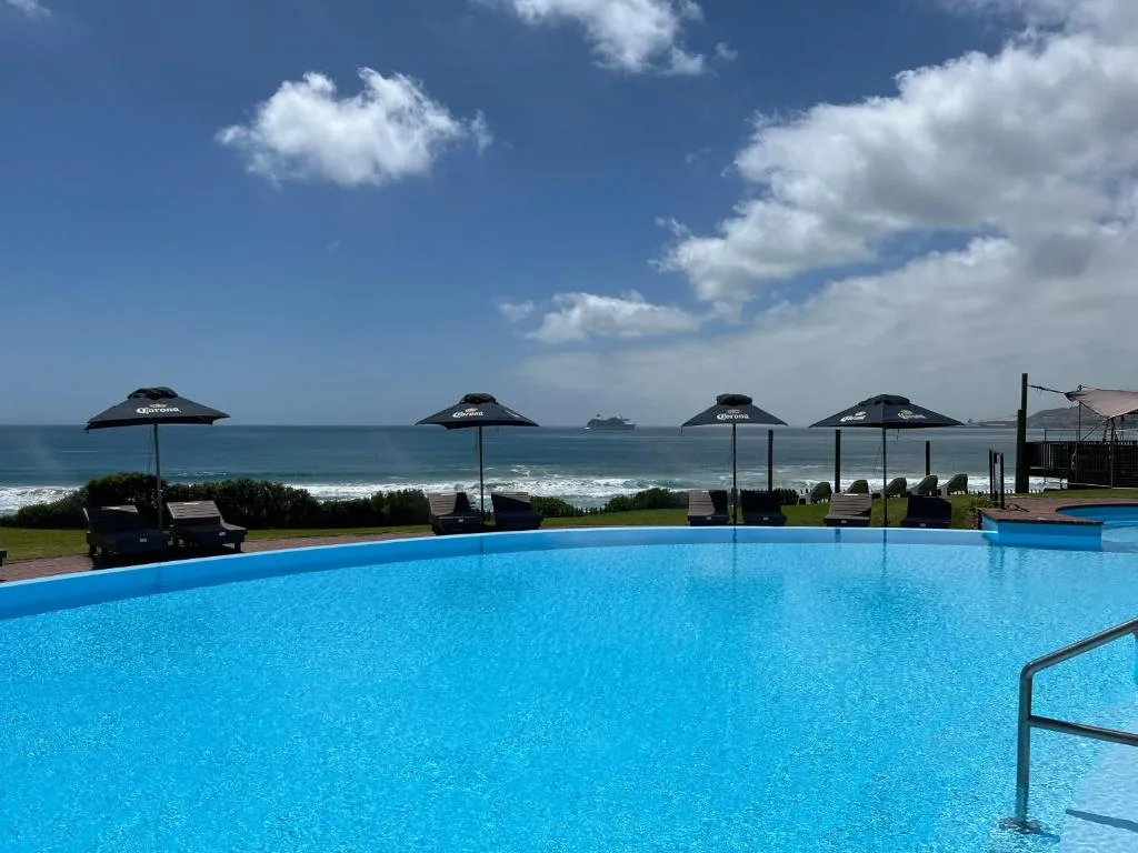 Oceanfront swimming pool with umbrellas overlooking turquoise waters
