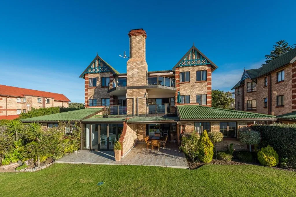 Victorian brick home with green roof and manicured garden facade