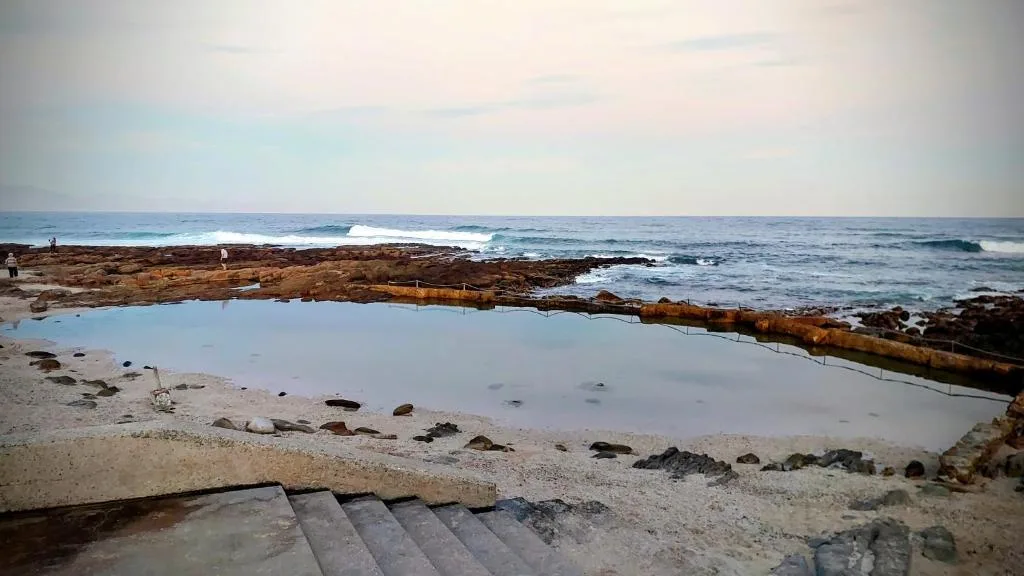 Scenic coastal view with ocean waves, sandy beach, and natural rock formations