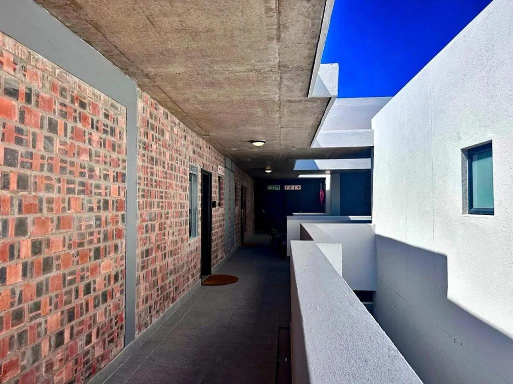 Modern covered breezeway with exposed brick walls and white railings