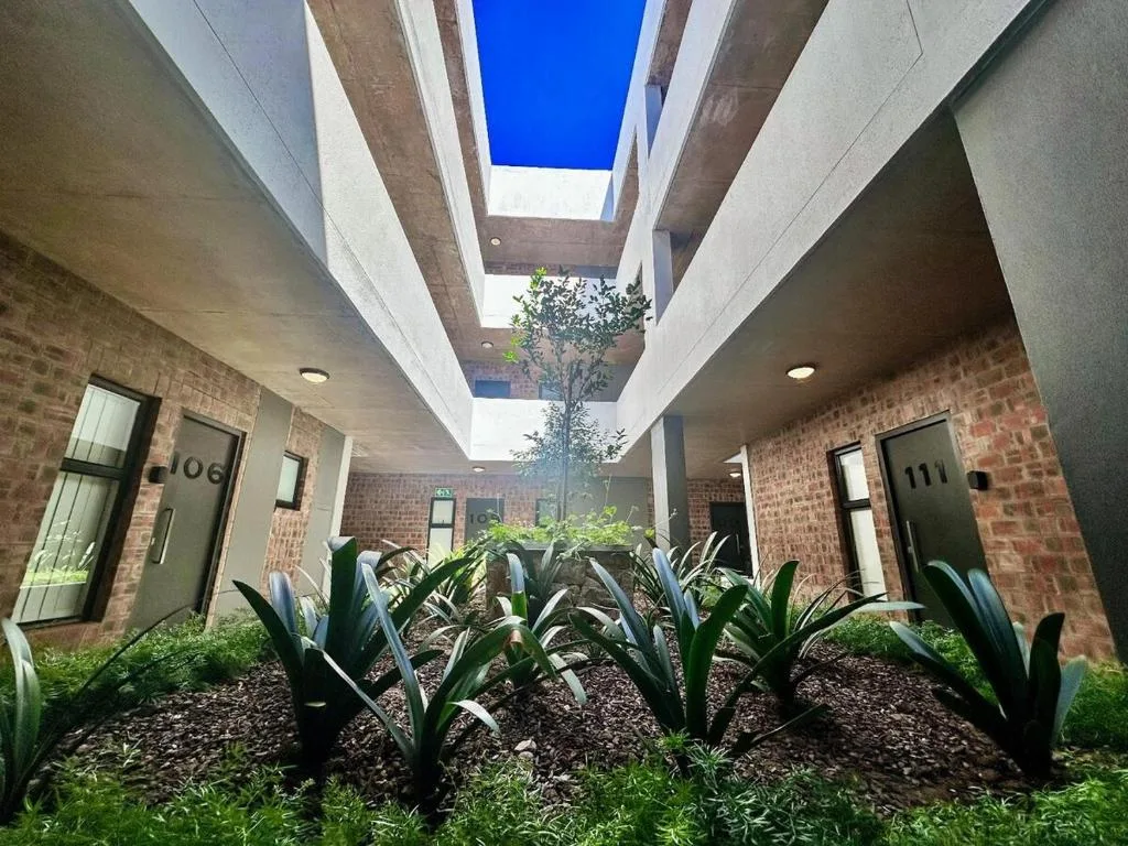 Modern courtyard with brick walls, skylights, and landscaped garden featuring plants