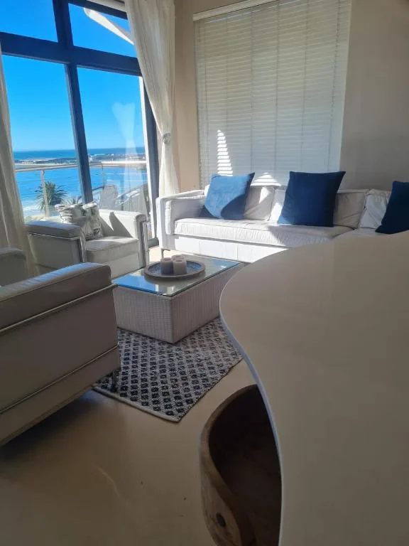 Bright lounge with ocean view through large windows and coastal pillows