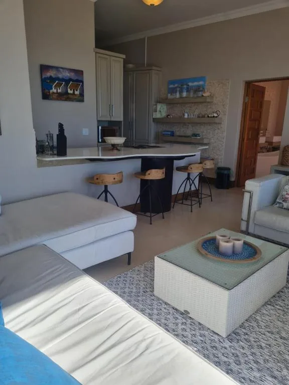 Open-plan lounge with sofa, kitchen counter seating, and modern furnishings