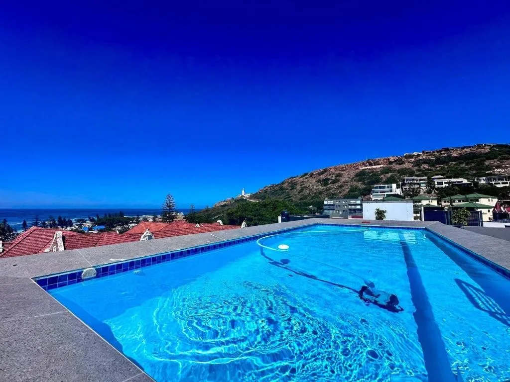 Sparkling blue swimming pool overlooking Mossel Bay and coastal mountains