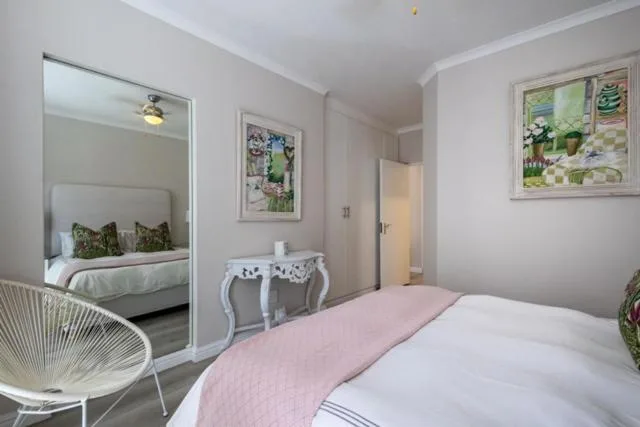 Bright bedroom with pink bedding, mirror, and comfortable furnishings