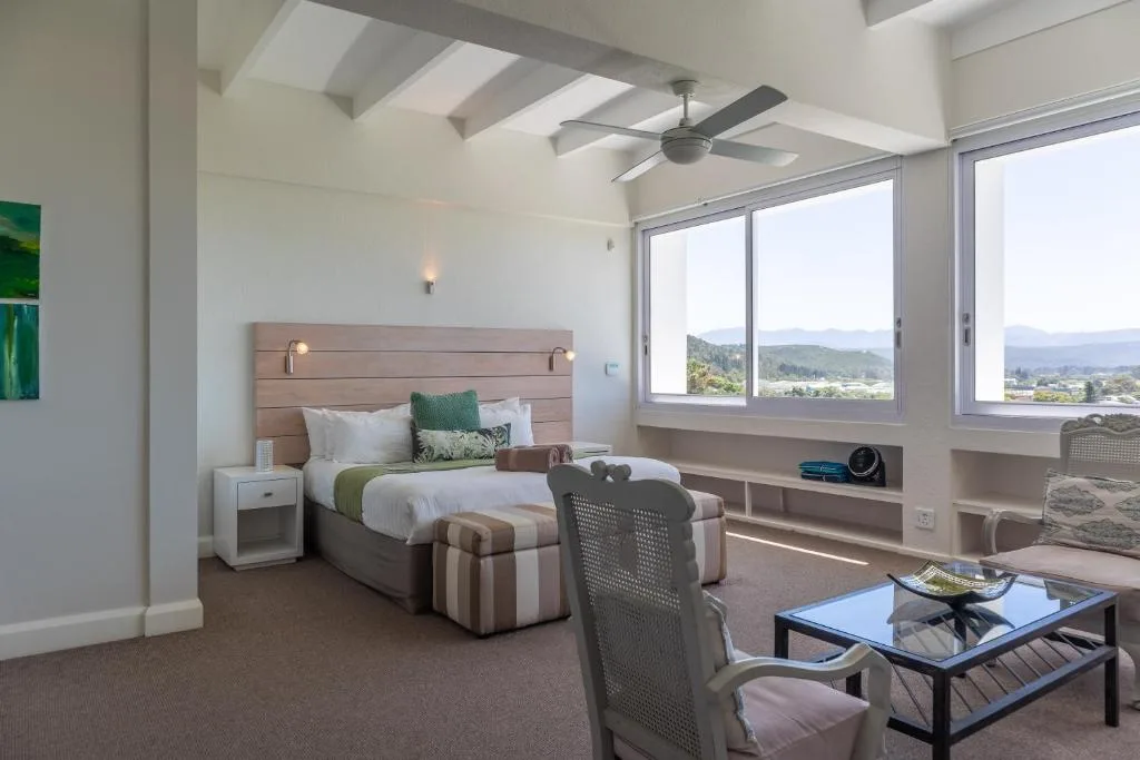 Bright bedroom with bed, mountain views through large windows, ceiling fan
