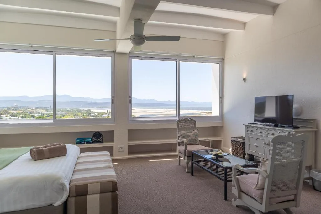 Bright bedroom with bed, TV, ceiling fan, and expansive lagoon views