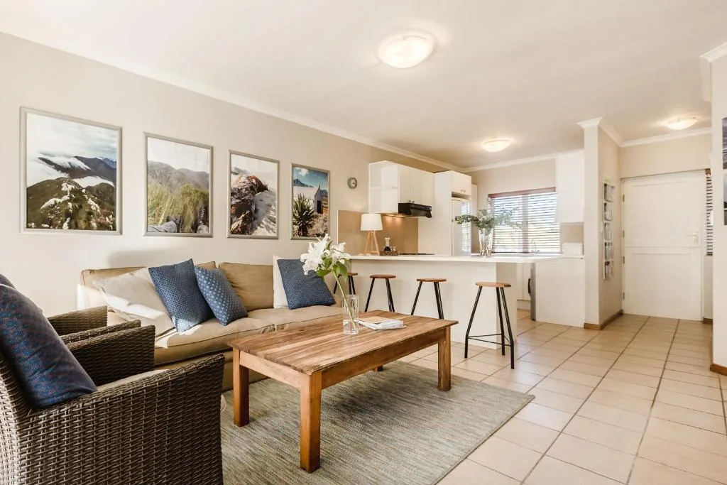 Open-plan lounge with rattan seating, wooden coffee table, and kitchen bar seating