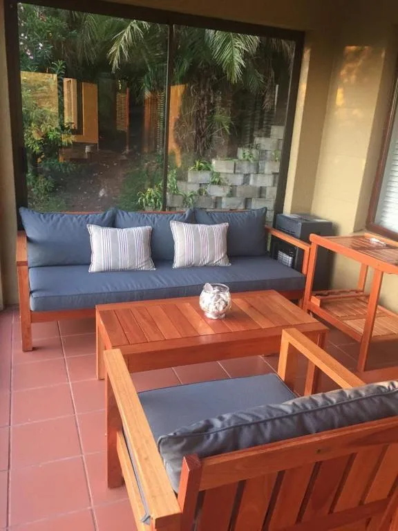Covered patio with wooden furniture and blue cushions overlooking garden