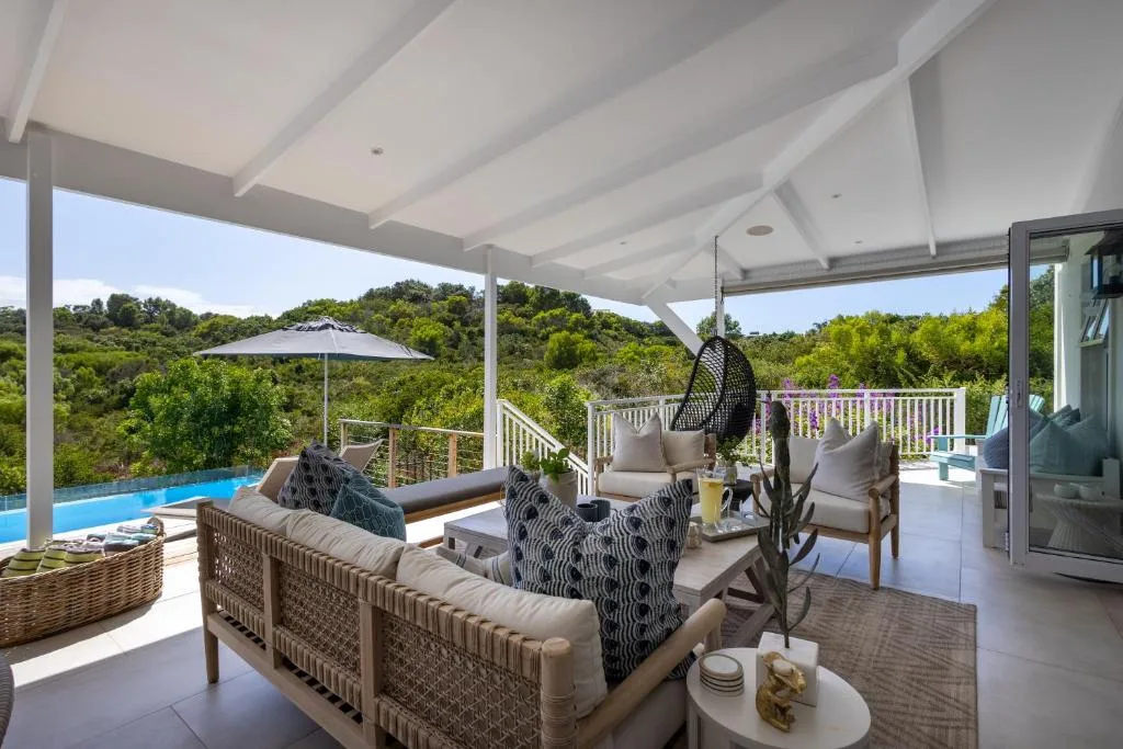 Covered outdoor entertaining area with seating, pool, and forest views