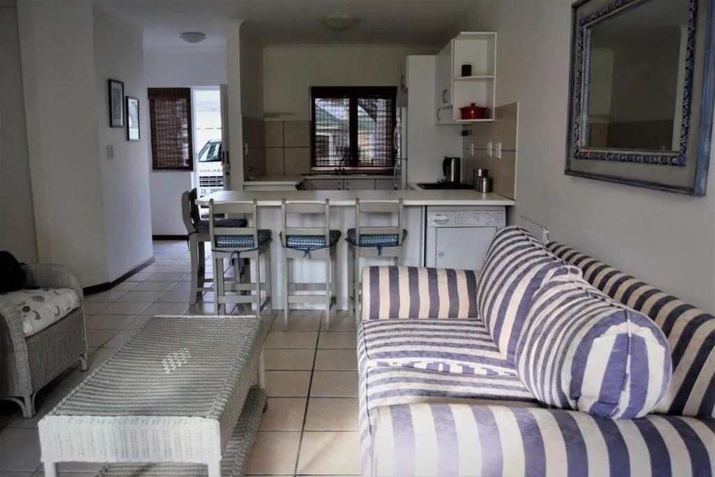 Open-plan lounge with striped sofa, kitchen counter seating, and ocean view