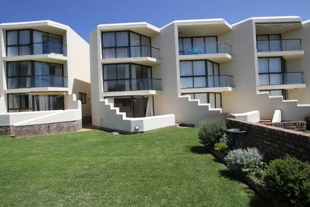 Modern white apartment building with manicured lawn and landscaping