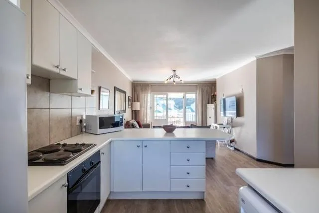 Modern open-plan kitchen with white cabinetry, gas stove, and ocean views