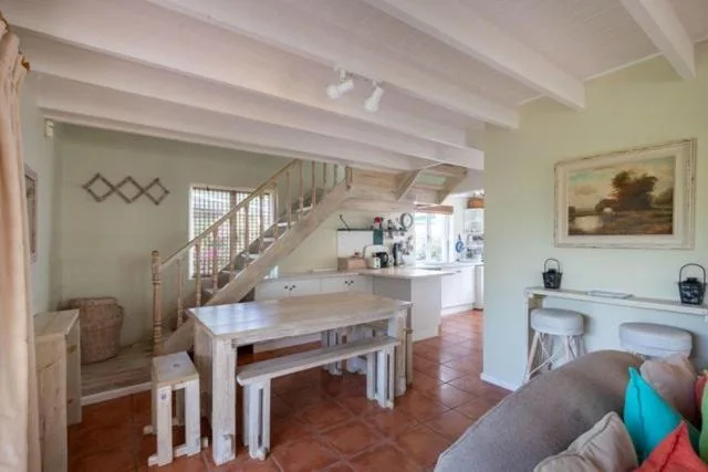 Open-plan dining area with wooden table and benches, staircase visible