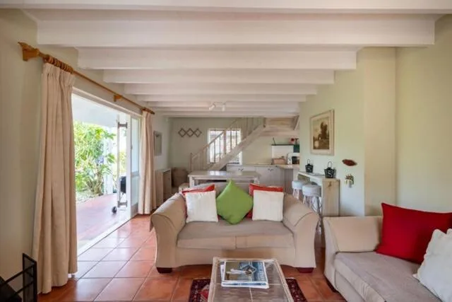 Spacious living room with beige sofas, colorful cushions, terracotta tiles