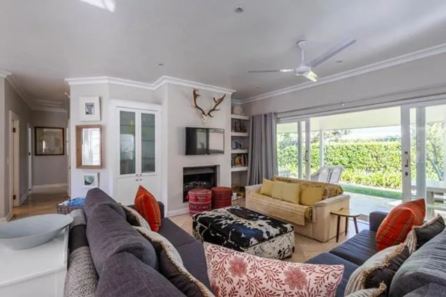 Spacious living room with gray sofas, fireplace, and garden views through large windows