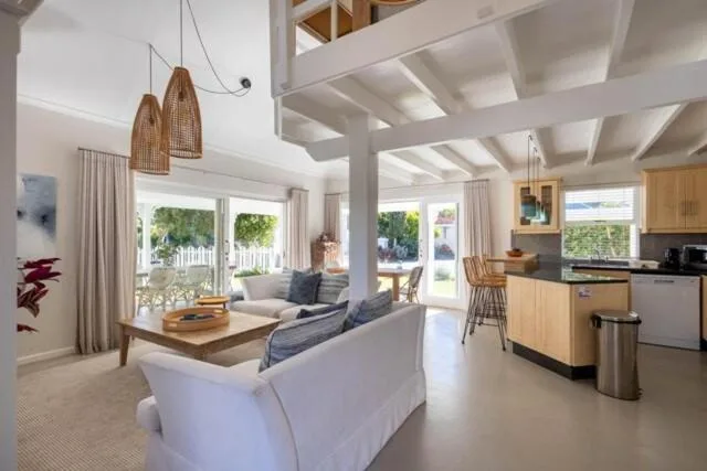 Bright open-plan lounge with white sofas, woven pendant lights, and garden views