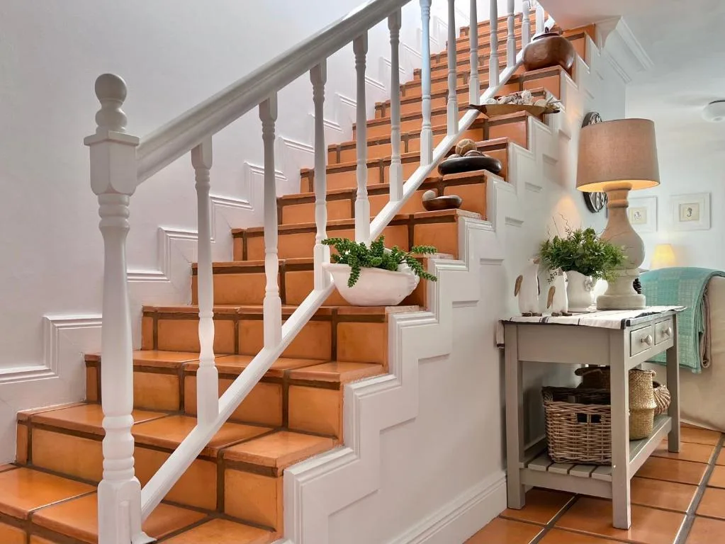 Elegant wooden staircase with white railings and decorative plant arrangement