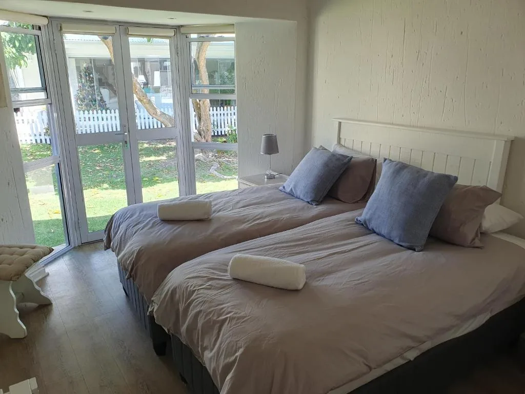 Bright bedroom with twin beds, garden views through glass doors
