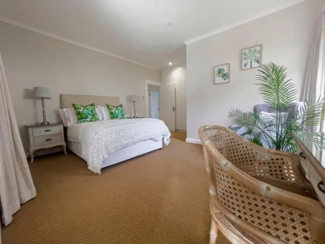 Spacious bedroom with queen bed, nightstands, plants, and seating area