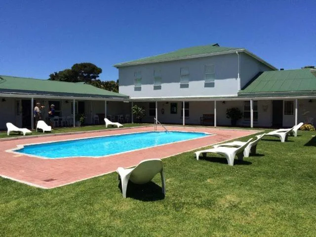 Rectangular swimming pool with loungers on manicured lawn and building