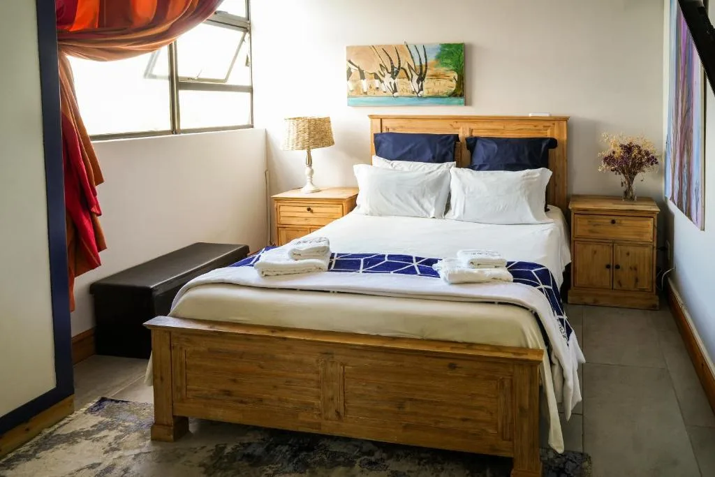 Bright bedroom with wooden bed frame, white linens, and bedside tables