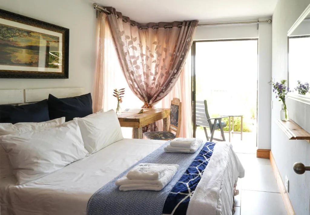 Bright bedroom with queen bed, fresh white linens, deck access, and garden views