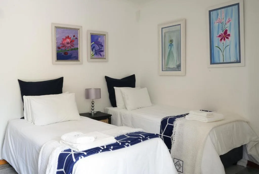 Twin bedroom with white linens, black headboards, and floral wall art