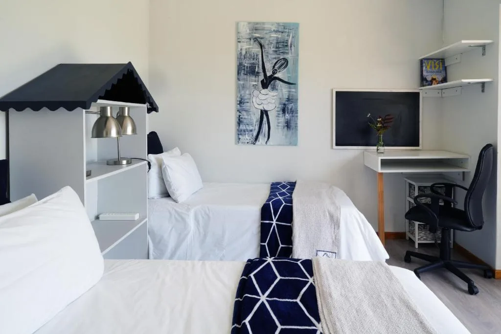 Bright bedroom with twin beds, desk area, and modern artwork on walls