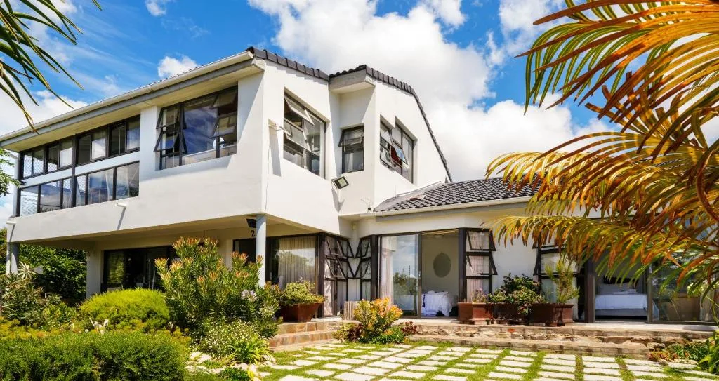 Modern white two-story house with landscaped garden and stepping stone pathway