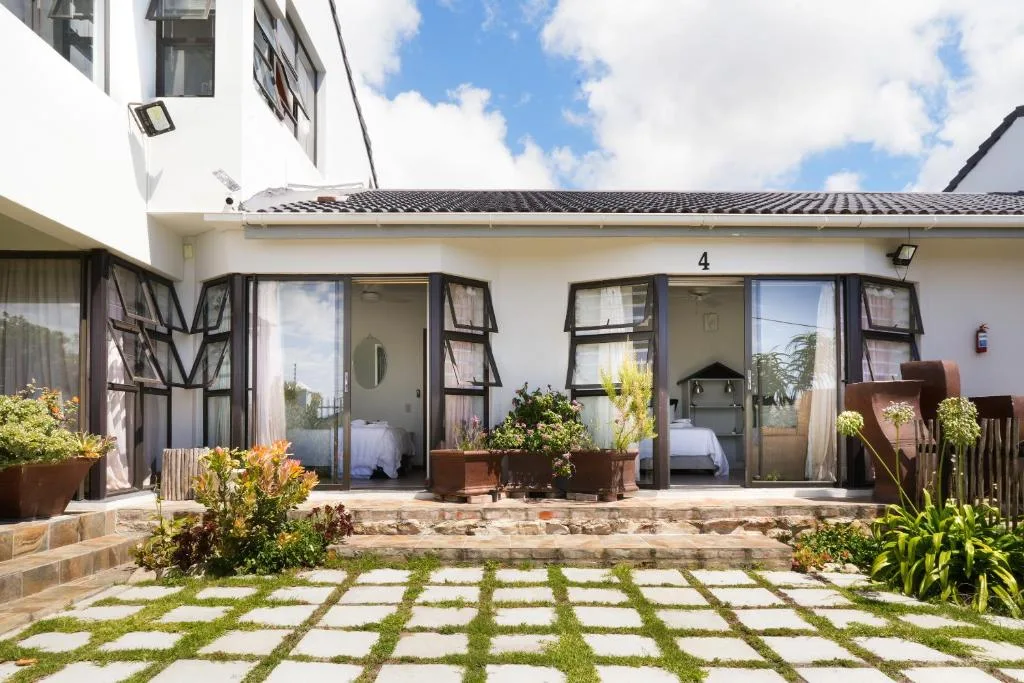 Modern white coastal home with paved courtyard and potted plants