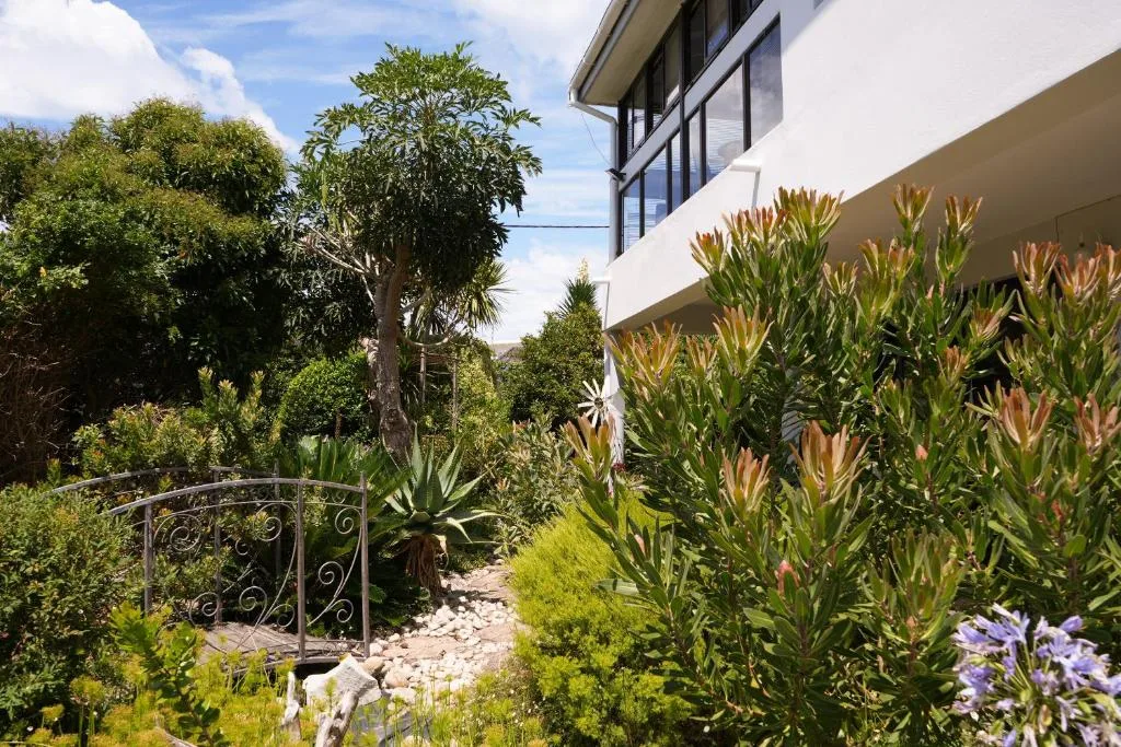 Modern white building exterior with lush garden landscaping and decorative gate