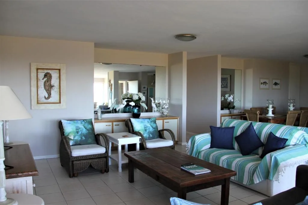 Spacious lounge with striped sofa, wicker chairs, and ocean-themed decor