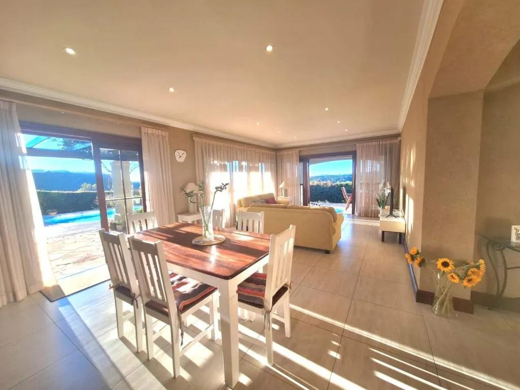 Open-plan lounge and dining area with panoramic lagoon and mountain views through large windows