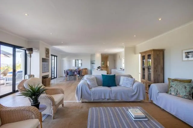 Spacious open-plan lounge with white sofas and ocean views through glass doors