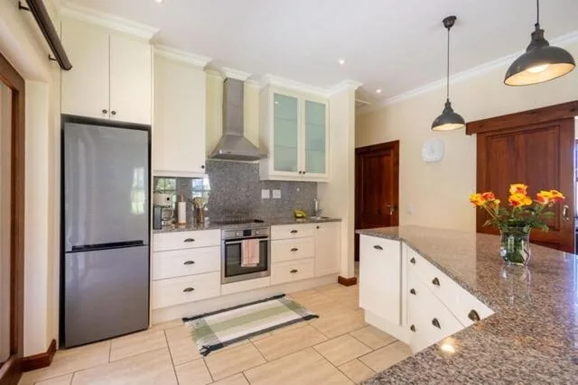 Modern kitchen with white cabinetry, stainless steel appliances, and granite countertop
