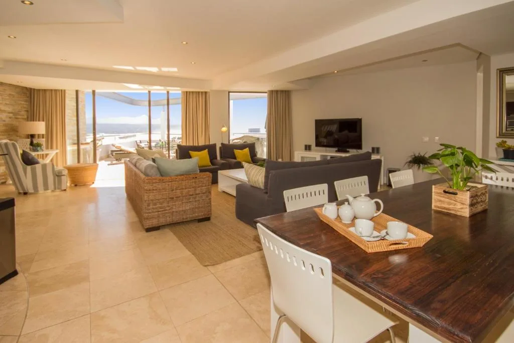 Spacious open-plan lounge with ocean views through large windows and coastal furnishings