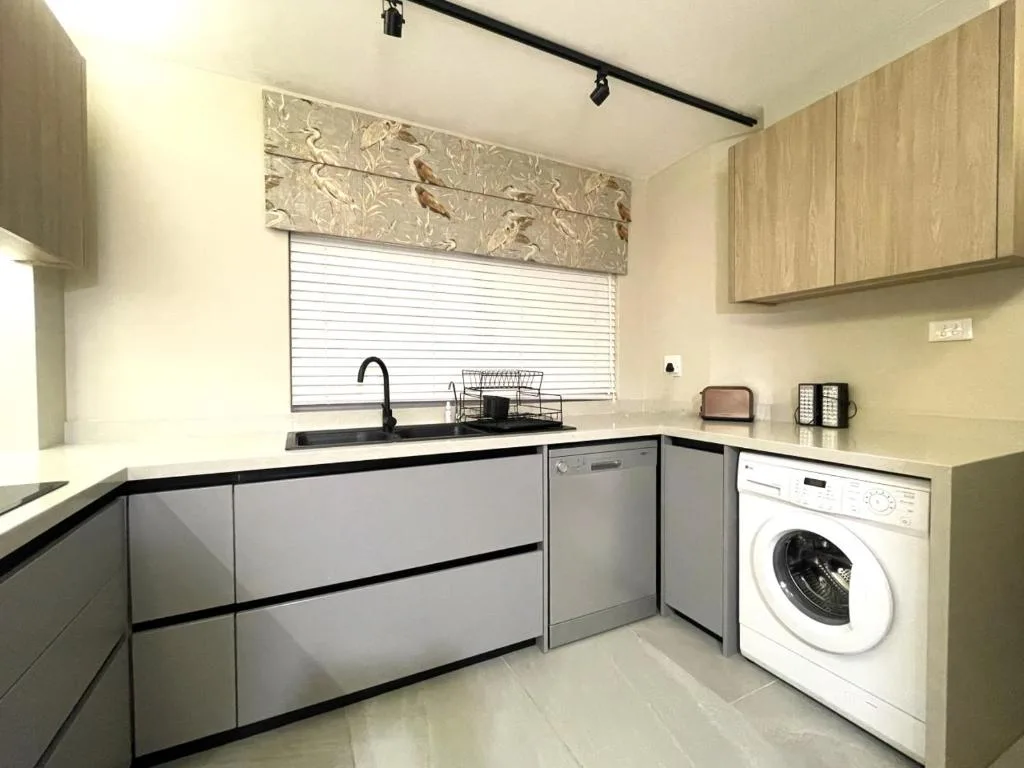 Modern kitchen with gray cabinetry, sink, dishwasher, and washing machine