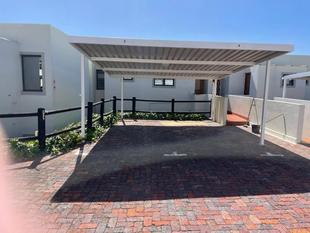 Modern white apartment building with covered carport and brick paved entrance