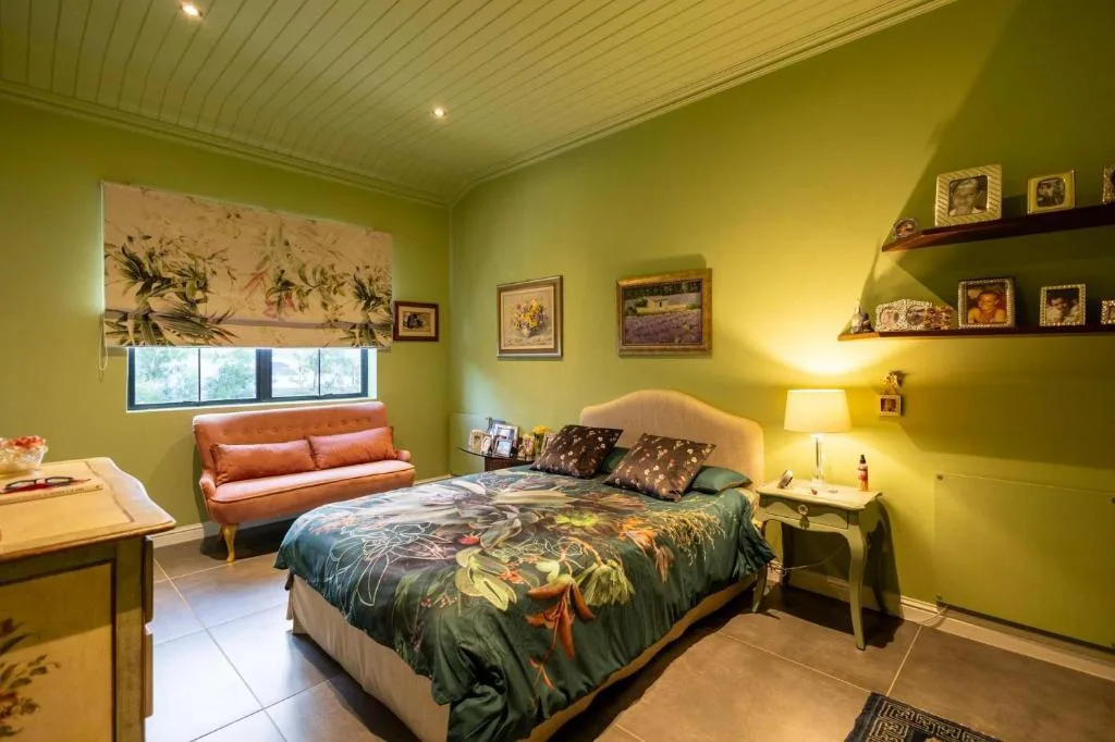 Bright green bedroom with queen bed, floral bedding, and cozy seating nook