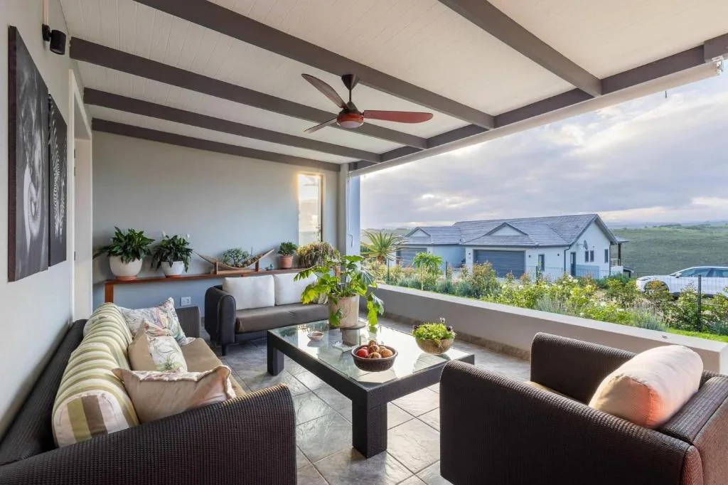 Covered outdoor patio with seating, potted plants, and countryside views