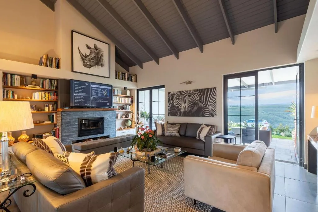 Modern lounge with fireplace, sofas, and panoramic garden route views