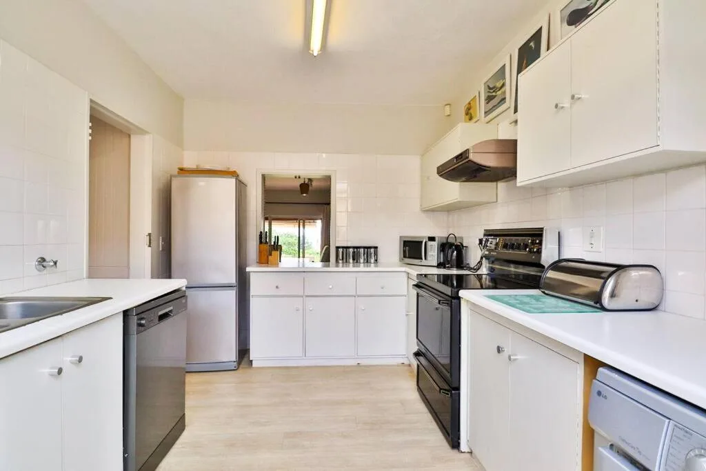 Bright white kitchen with stainless appliances and wooden countertops