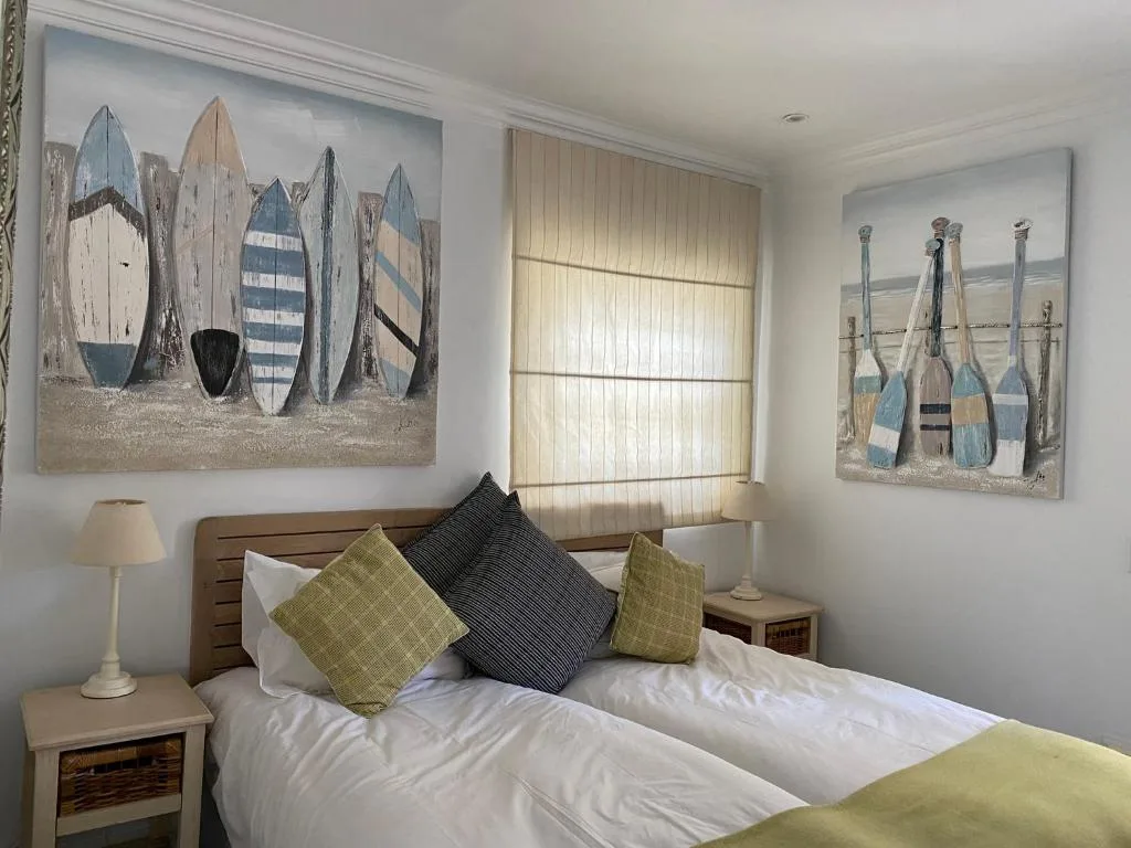 Bright bedroom with queen bed, nautical artwork, coastal decor pillows