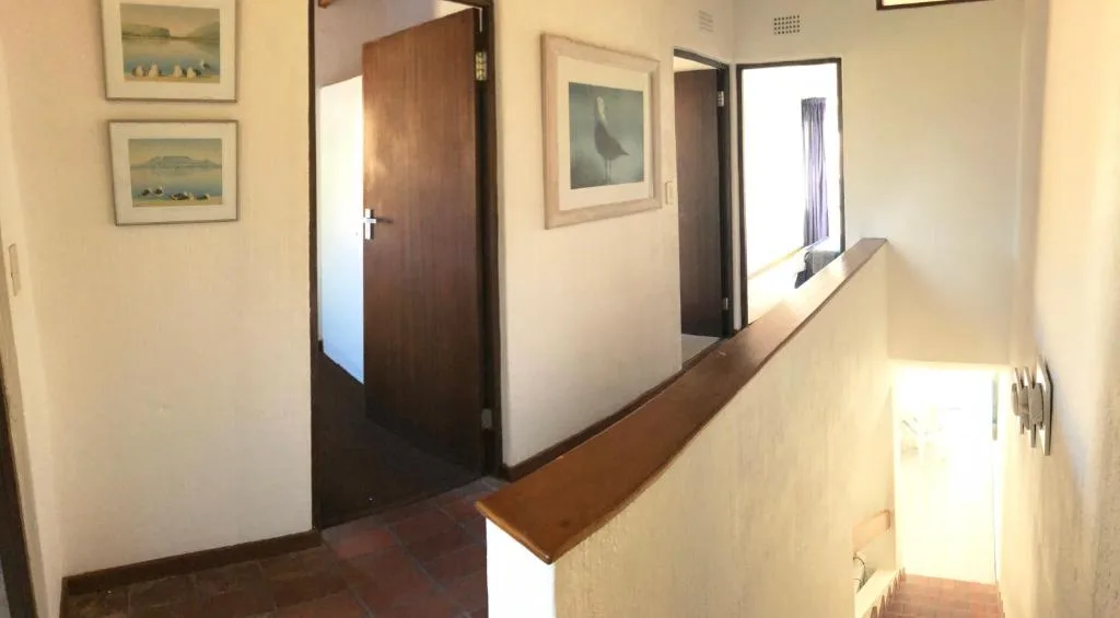 Hallway with framed artwork, wooden doors, and neutral decor throughout