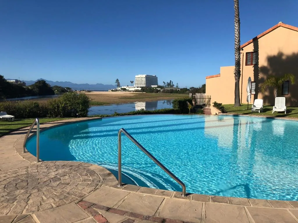 Large sparkling swimming pool with lagoon and mountain views beyond